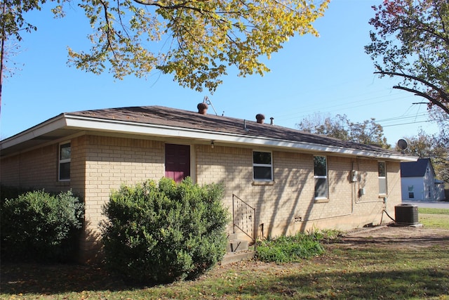 view of side of property with a lawn and cooling unit