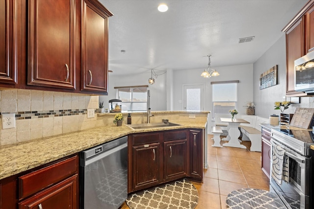 kitchen with a wealth of natural light, sink, light stone countertops, and appliances with stainless steel finishes