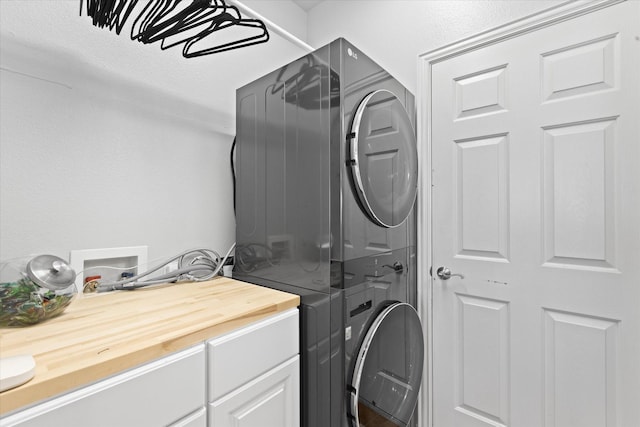 clothes washing area featuring cabinets and stacked washer and dryer