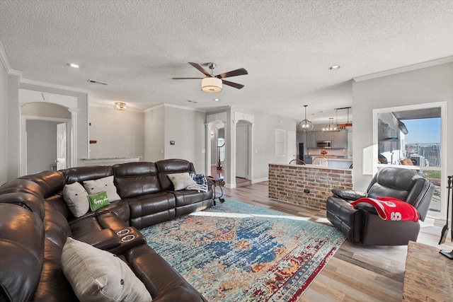 living room with ornate columns, crown molding, ceiling fan, and light hardwood / wood-style floors