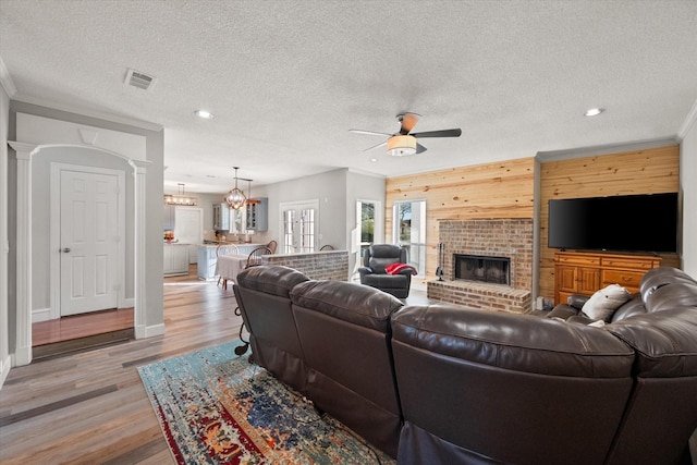 living room with ceiling fan, ornamental molding, light hardwood / wood-style floors, and decorative columns