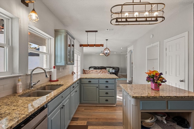 kitchen featuring dishwasher, light stone countertops, a center island, and pendant lighting