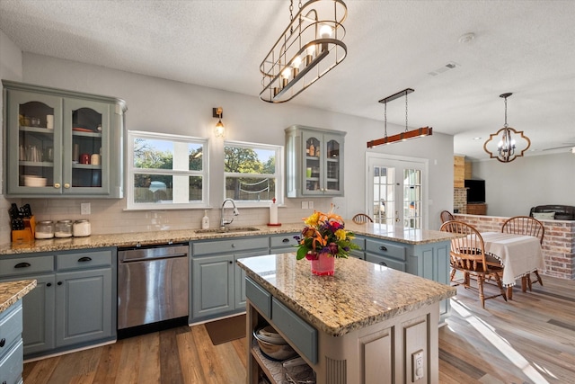 kitchen featuring gray cabinets, decorative light fixtures, dishwasher, sink, and a center island