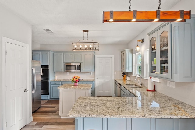 kitchen with a kitchen island, sink, hanging light fixtures, kitchen peninsula, and stainless steel appliances