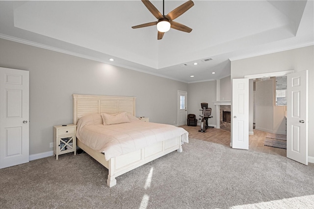 bedroom with a raised ceiling, crown molding, and carpet floors