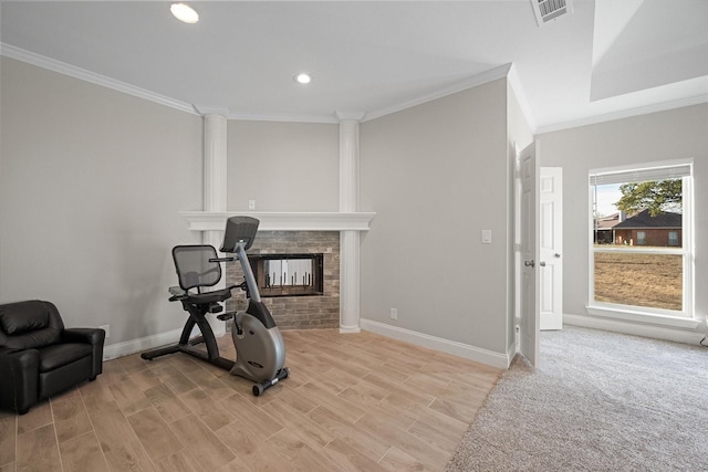 workout area featuring crown molding, decorative columns, and light wood-type flooring