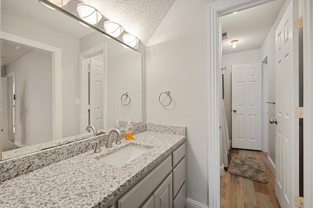 bathroom featuring vanity, hardwood / wood-style flooring, and a textured ceiling