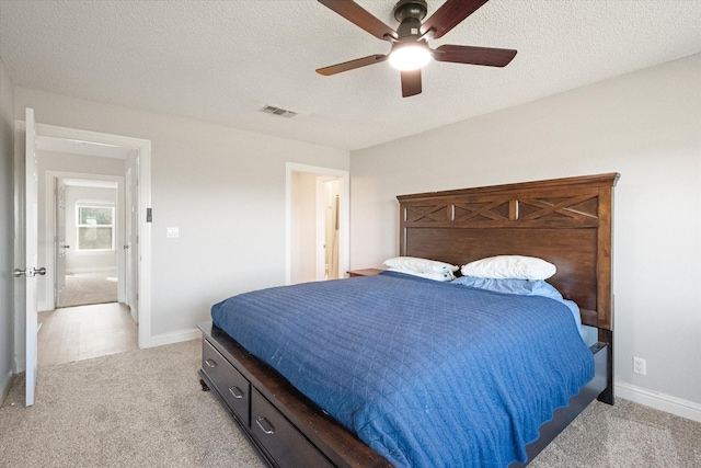 bedroom featuring ceiling fan, light colored carpet, and a textured ceiling