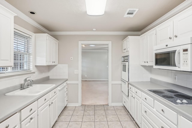 kitchen featuring sink, white cabinets, crown molding, white appliances, and light tile patterned floors