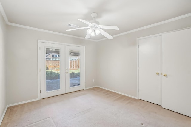 empty room featuring crown molding, french doors, ceiling fan, and light colored carpet