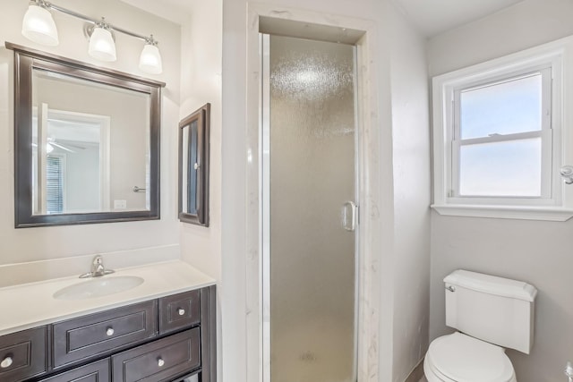 bathroom with vanity, toilet, an enclosed shower, and ceiling fan