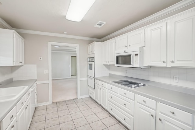 kitchen with white appliances, sink, light tile patterned floors, ornamental molding, and white cabinetry