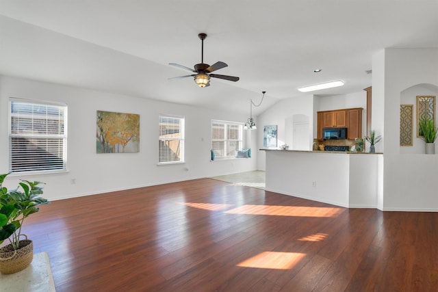 unfurnished living room with ceiling fan with notable chandelier, dark wood-type flooring, and lofted ceiling