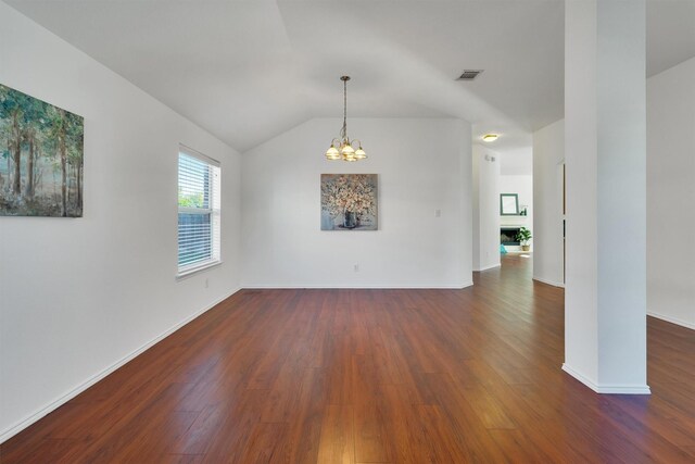 spare room featuring a notable chandelier, dark wood-type flooring, and vaulted ceiling