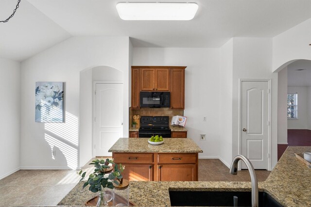 kitchen with black appliances, a healthy amount of sunlight, light stone countertops, and sink