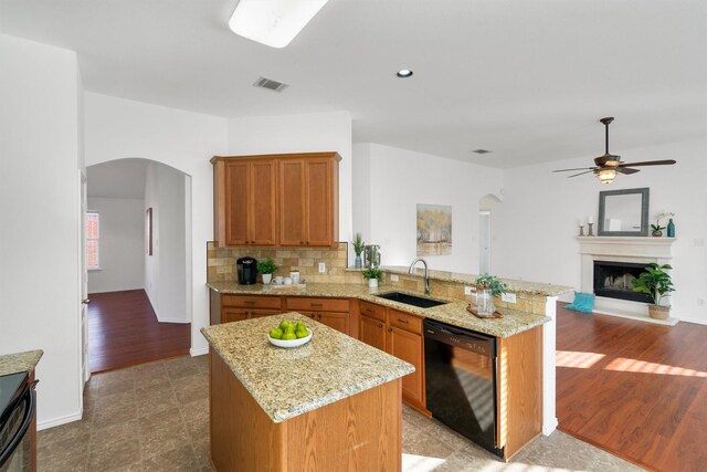 kitchen featuring kitchen peninsula, backsplash, sink, hardwood / wood-style flooring, and dishwasher