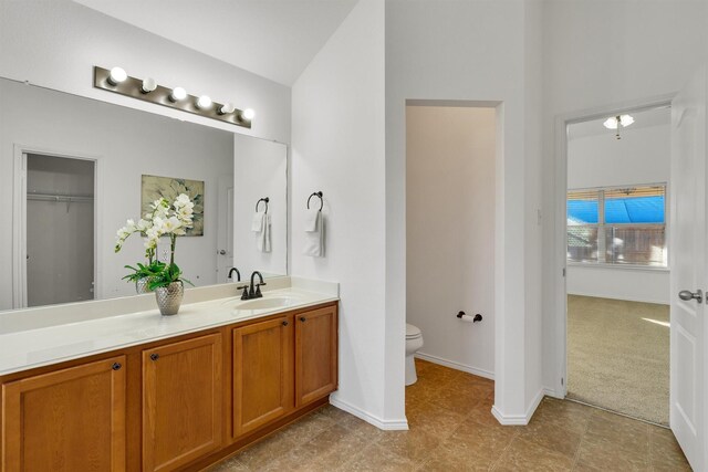 bathroom with vanity, toilet, and lofted ceiling