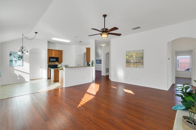 unfurnished living room featuring dark wood-type flooring, vaulted ceiling, and ceiling fan with notable chandelier