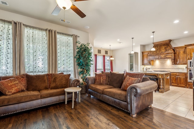 living room with light hardwood / wood-style floors and ceiling fan with notable chandelier