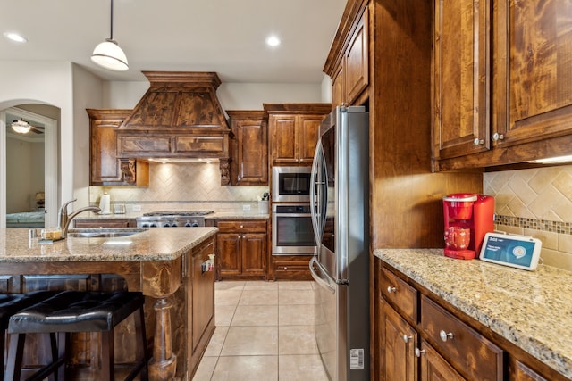 kitchen featuring backsplash, sink, decorative light fixtures, custom range hood, and stainless steel appliances