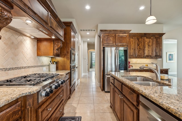 kitchen featuring tasteful backsplash, stainless steel appliances, sink, light tile patterned floors, and decorative light fixtures