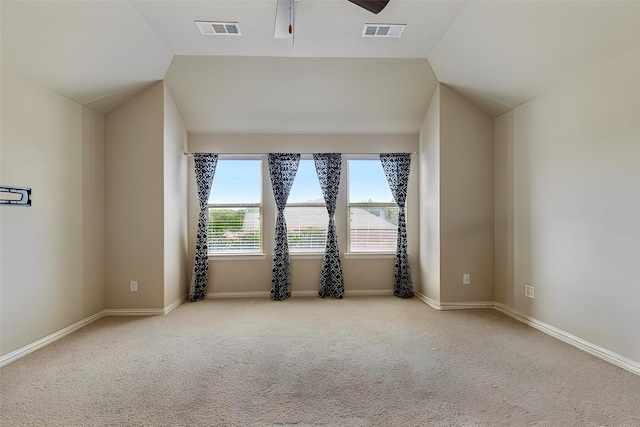 carpeted empty room with plenty of natural light, ceiling fan, and vaulted ceiling