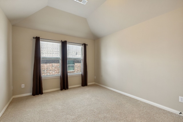 carpeted empty room with vaulted ceiling