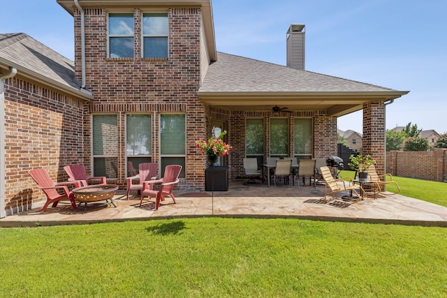 back of property with ceiling fan, a patio area, a yard, and an outdoor fire pit