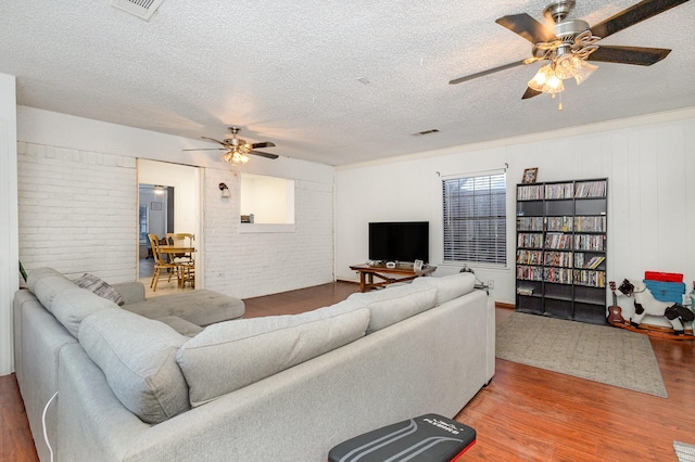 living room with ceiling fan, wood-type flooring, and a textured ceiling