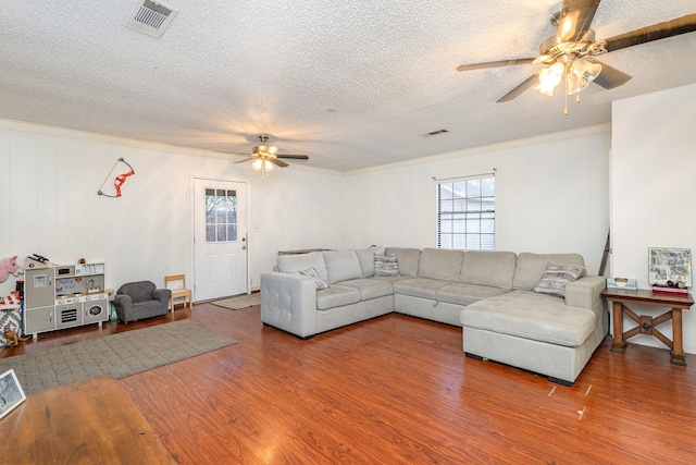 living room featuring hardwood / wood-style flooring, ornamental molding, a textured ceiling, and ceiling fan