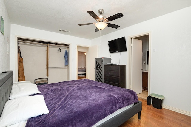 bedroom with ceiling fan, hardwood / wood-style flooring, a closet, and a textured ceiling