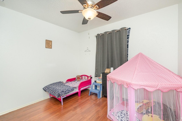 bedroom with ceiling fan, hardwood / wood-style floors, and a textured ceiling