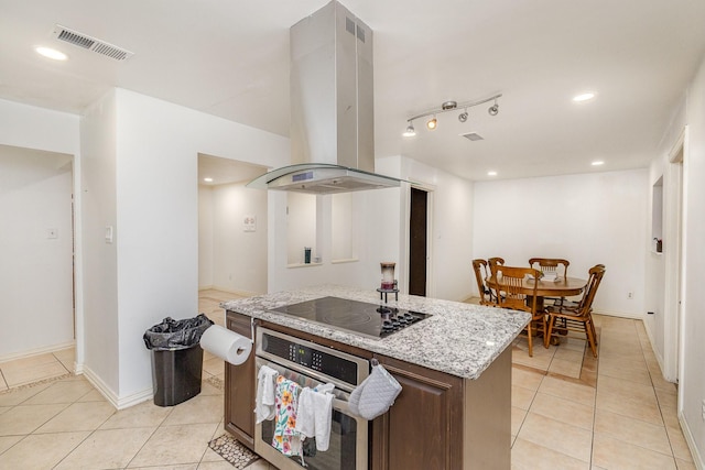 kitchen with light stone counters, stainless steel oven, black electric cooktop, island range hood, and light tile patterned floors