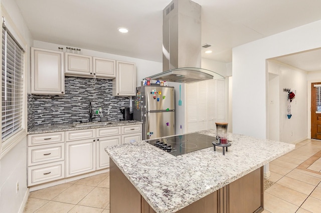 kitchen with sink, black electric cooktop, a kitchen island, island exhaust hood, and stainless steel refrigerator