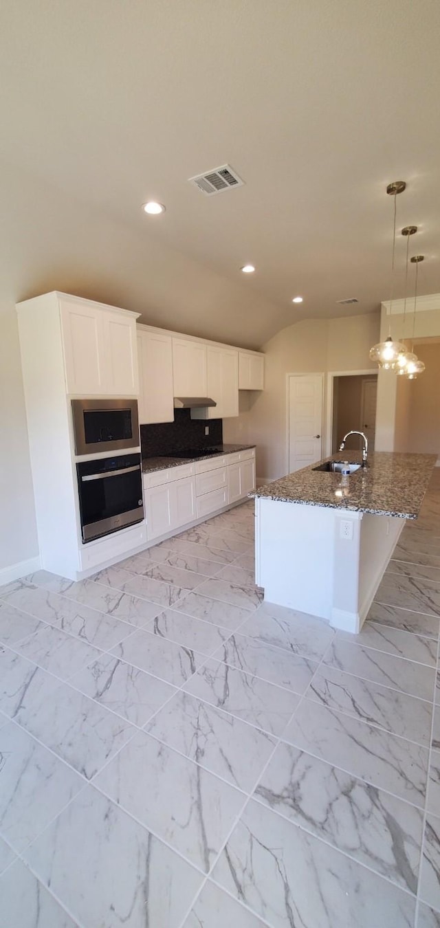 kitchen with white cabinets, decorative light fixtures, sink, oven, and dark stone countertops