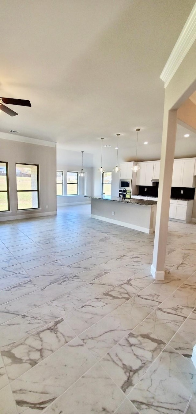 unfurnished living room with ornamental molding and ceiling fan