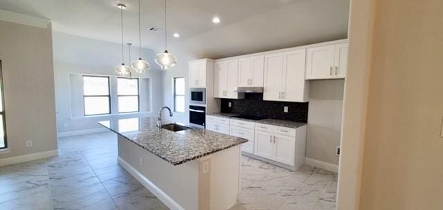 kitchen with sink, a kitchen island with sink, white cabinets, and hanging light fixtures