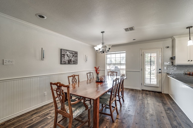 dining area featuring crown molding, dark wood-type flooring, a textured ceiling, and an inviting chandelier