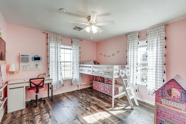 bedroom featuring ceiling fan, dark hardwood / wood-style floors, multiple windows, and a textured ceiling