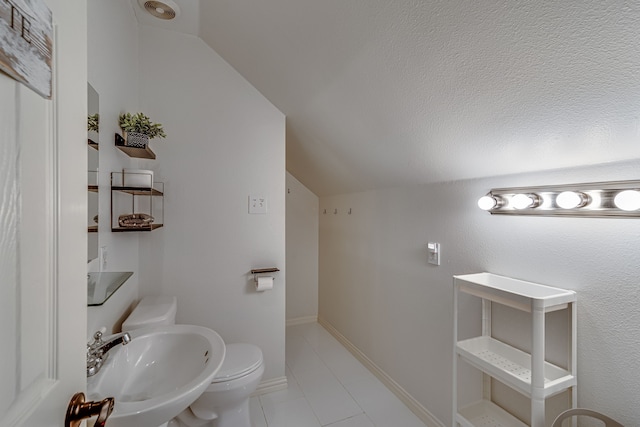 bathroom with lofted ceiling, toilet, sink, a textured ceiling, and tile patterned flooring