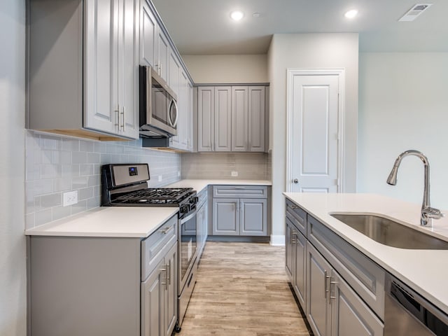 kitchen featuring gray cabinets, light hardwood / wood-style floors, sink, and stainless steel appliances