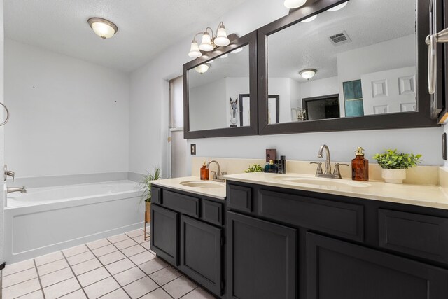 bathroom featuring a washtub, a textured ceiling, vanity, and tile patterned floors