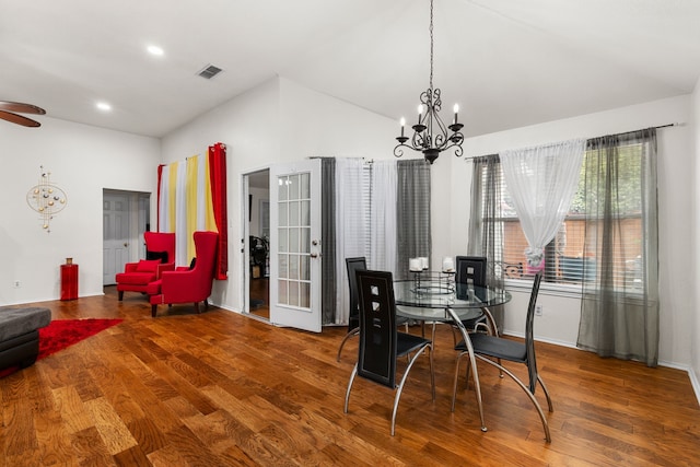 dining area with hardwood / wood-style floors, an inviting chandelier, and lofted ceiling