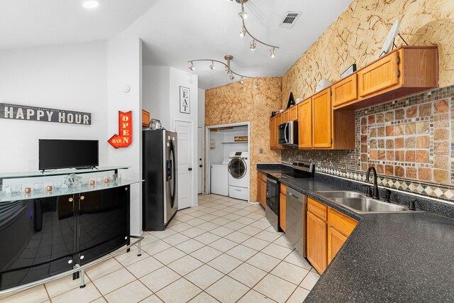 kitchen featuring sink, separate washer and dryer, backsplash, light tile patterned floors, and appliances with stainless steel finishes