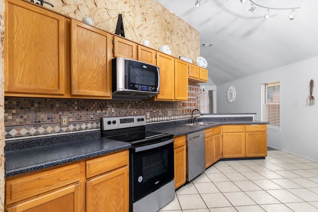 kitchen with tasteful backsplash, stainless steel appliances, sink, lofted ceiling, and light tile patterned flooring