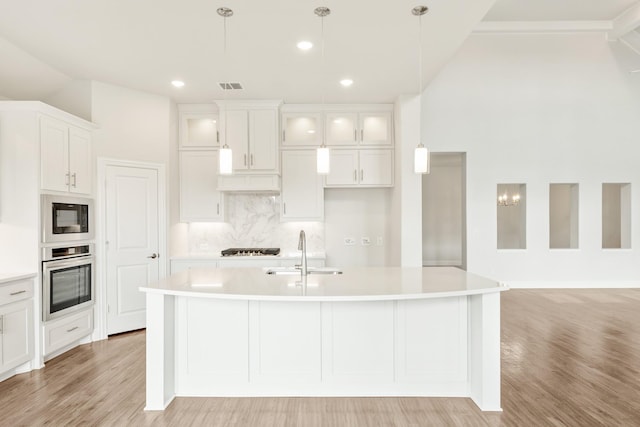 kitchen featuring glass insert cabinets, light countertops, stainless steel oven, and white cabinetry