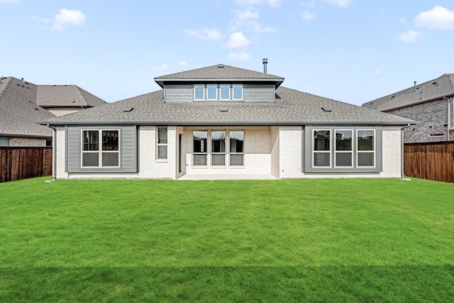 back of property featuring a fenced backyard, a shingled roof, a lawn, and brick siding