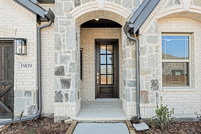 view of exterior entry featuring stone siding and brick siding