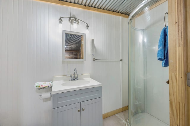 bathroom featuring vanity, a shower with shower door, and wood walls