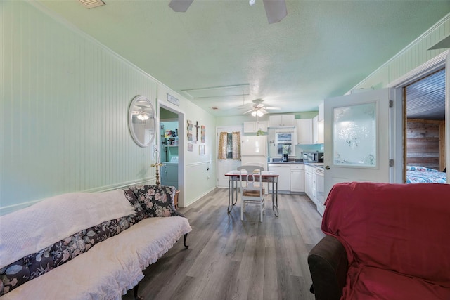 living room with washer / dryer, light wood-type flooring, ceiling fan, and ornamental molding